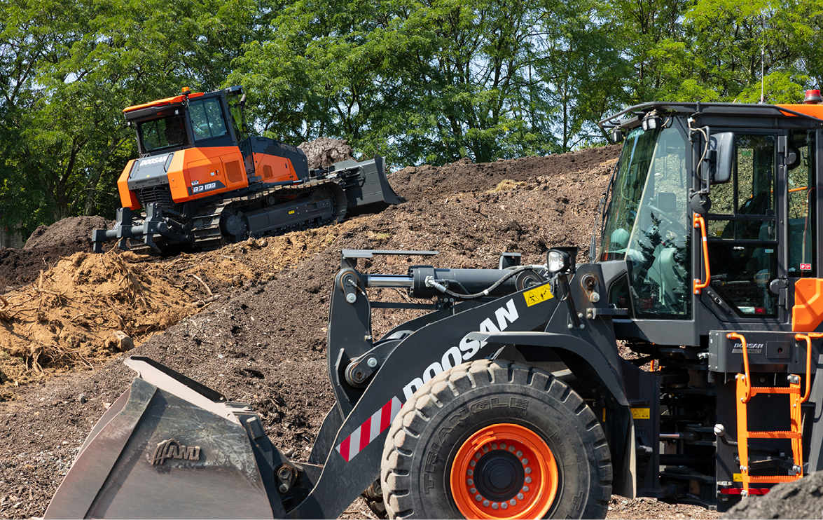 Photo of Doosan wheel loader dumping material into a Doosan articulated dump truck. 