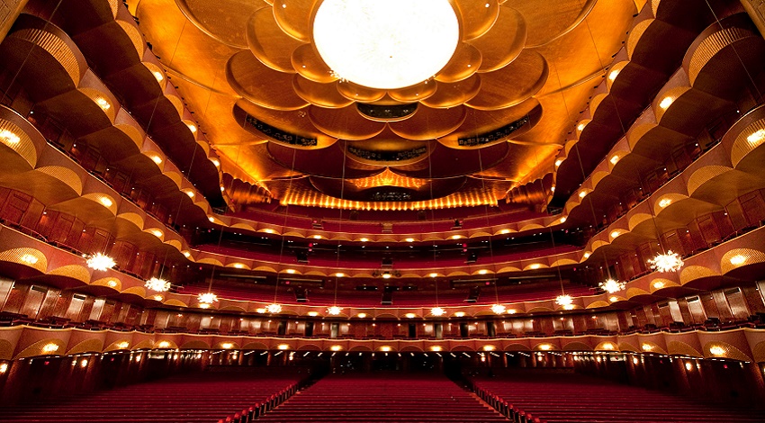 The interior of the Metropolitan Opera House in New York City, with many levels of seats and bright lights