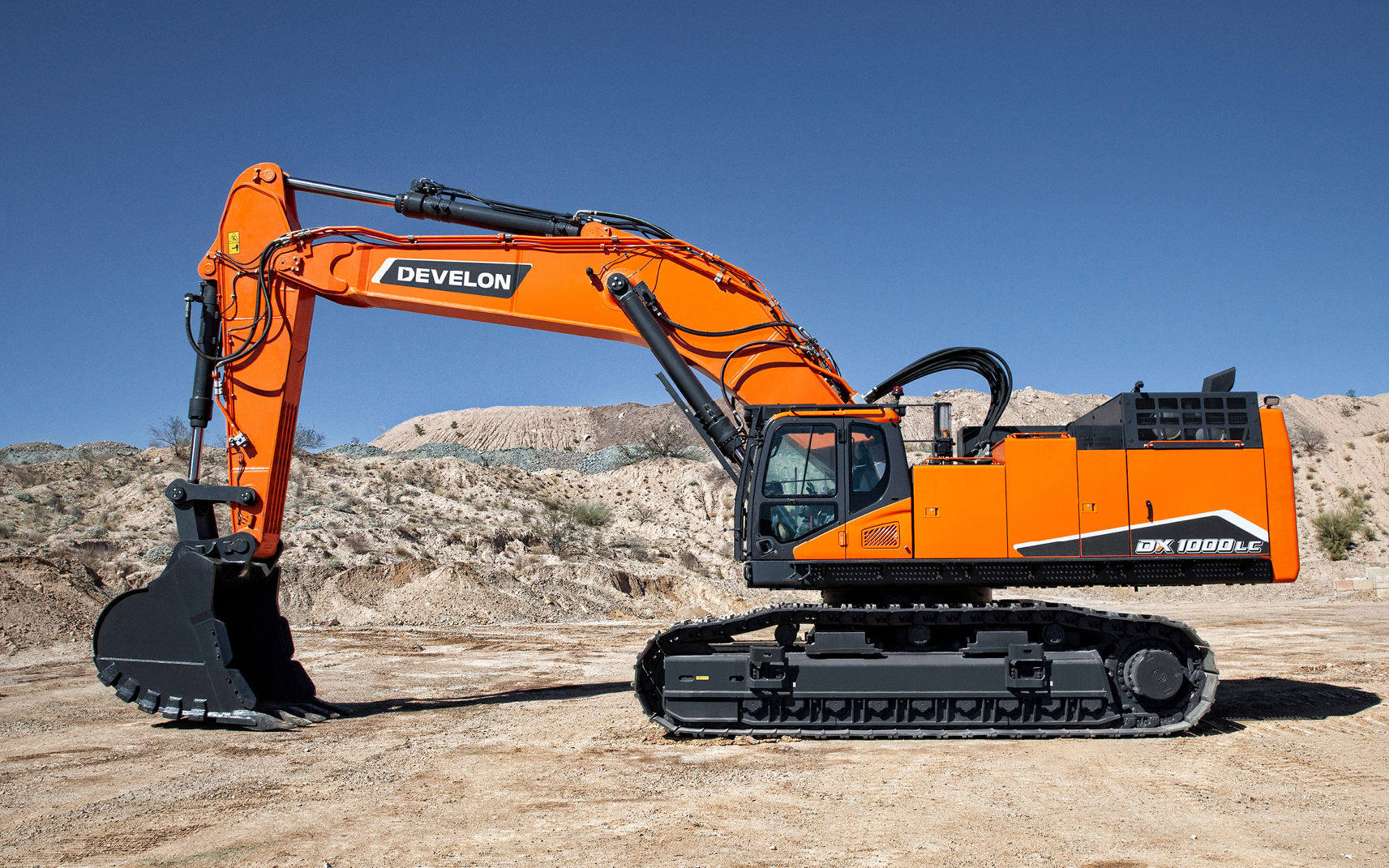 Profile view of a DEVELON crawler excavator at a job site.