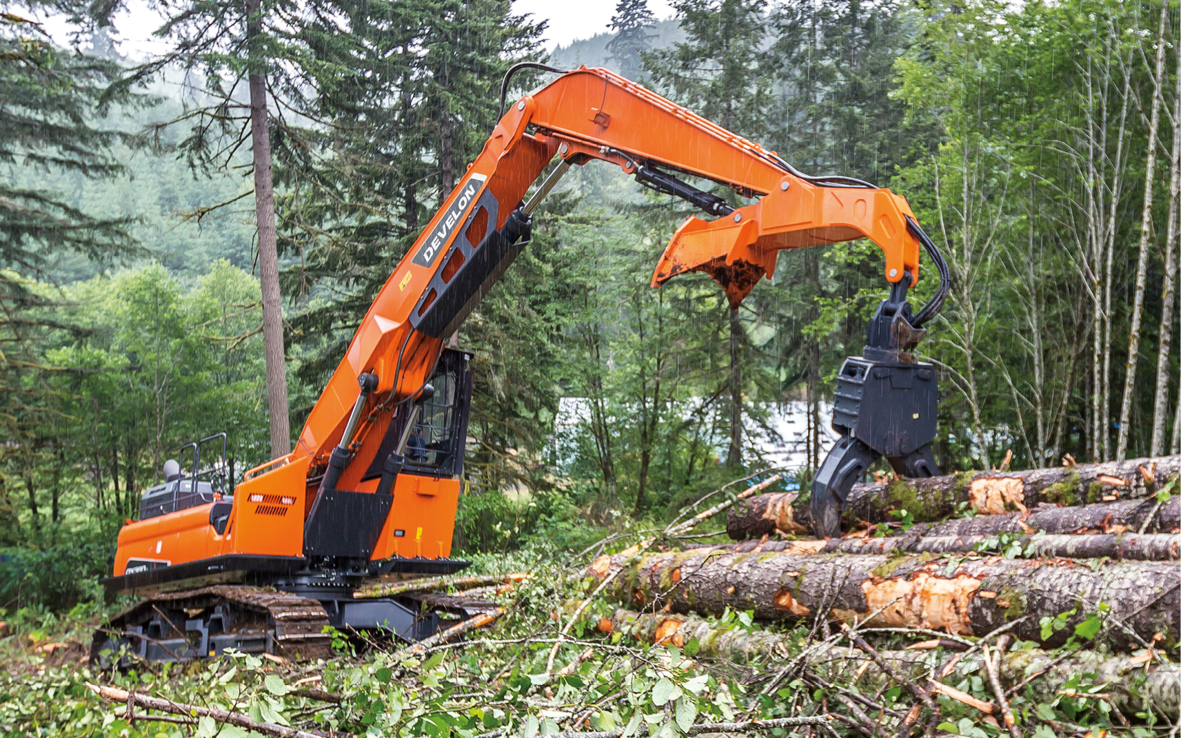 A DEVELON log loader placing a large tree in a pile of timber.