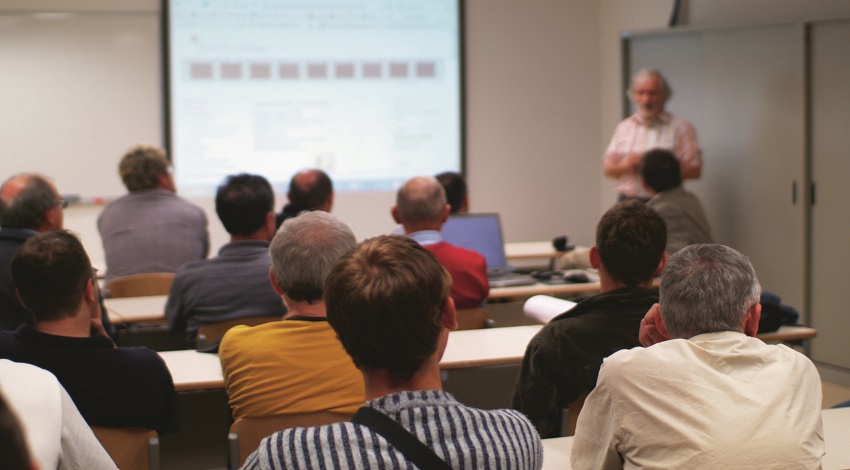 A classroom setting, where adults are listening to a lecturer