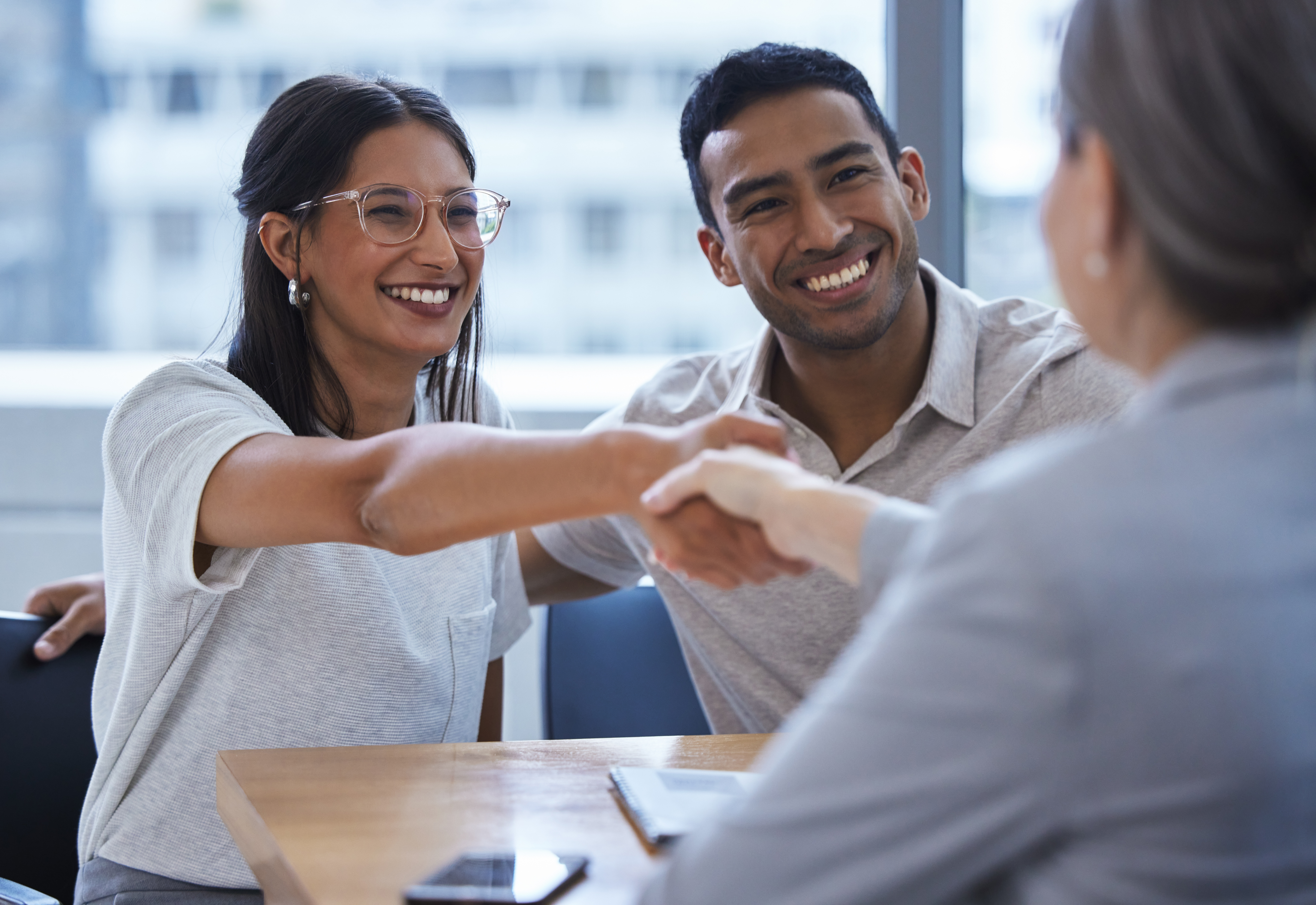 Hispanic Couple Shakes Hands in Office With Their Insurance Agent