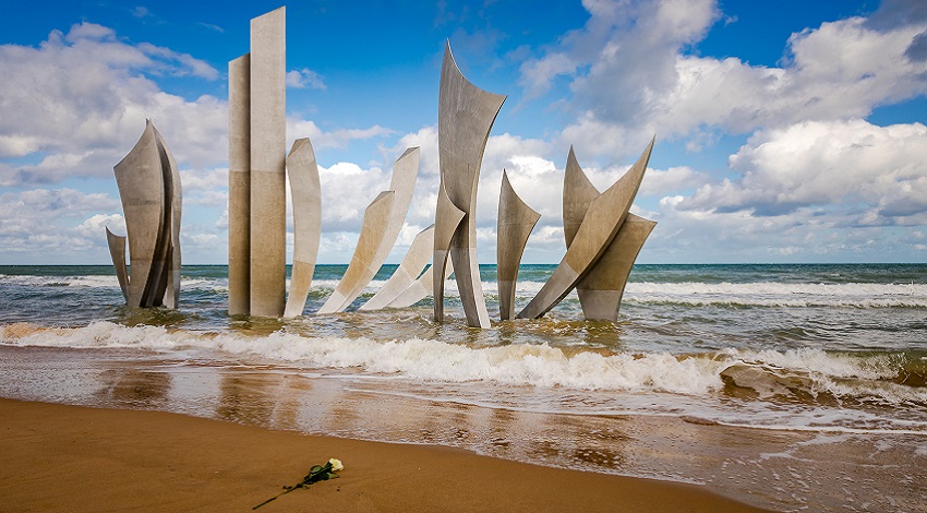 The Wings of Fraternity Monument at Omaha Beach with a rose placed on the sand in front