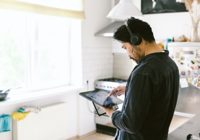 man in kitchen using tablet wearing headset